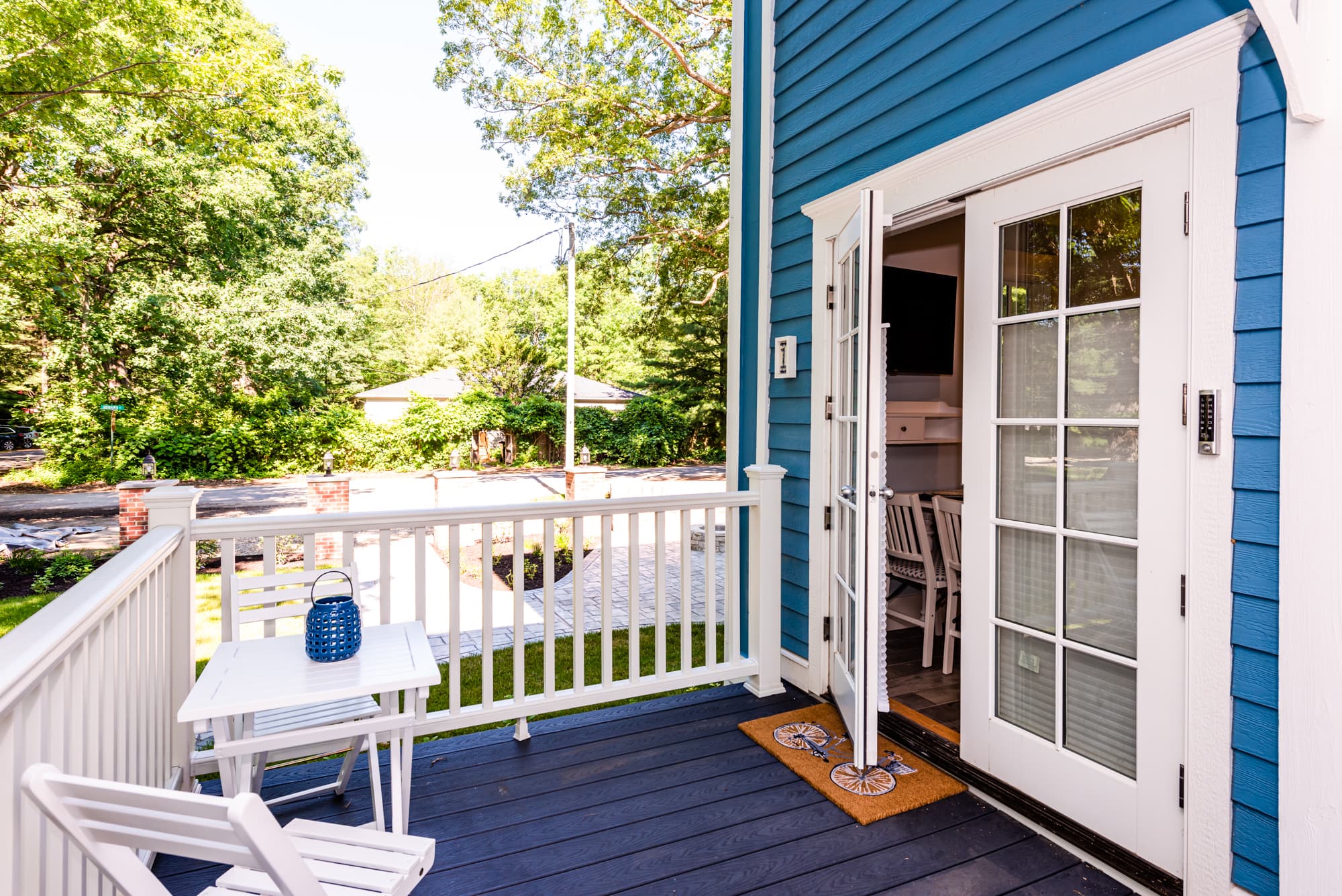 A private, white wooden deck with a small bistro table and two folding chairs.