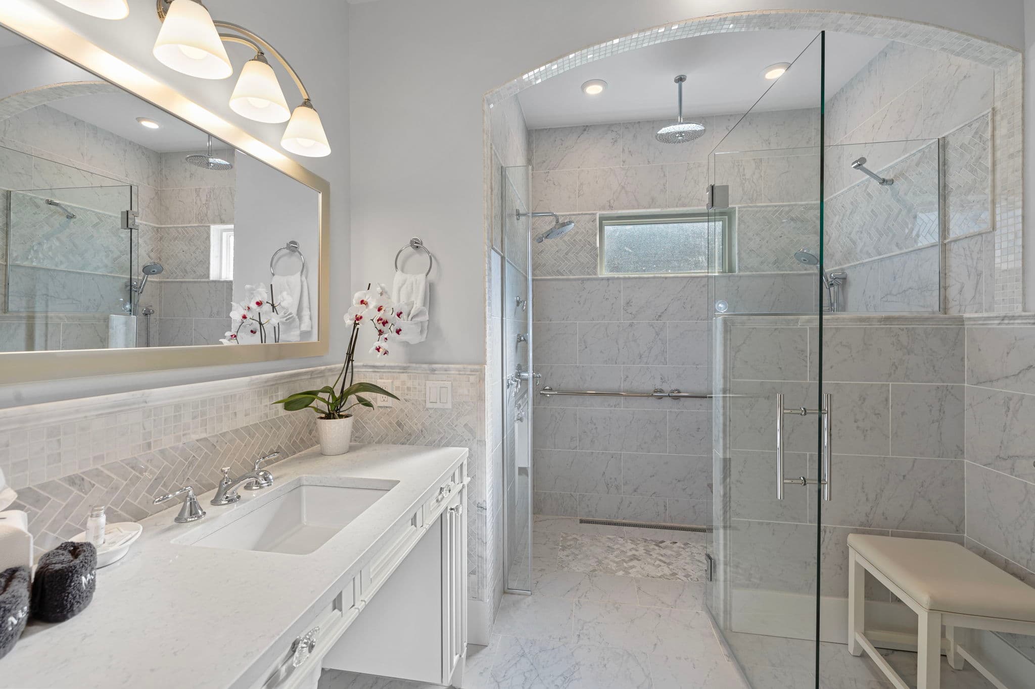 Walk in shower has multiple shower sprays, grab bars and bench