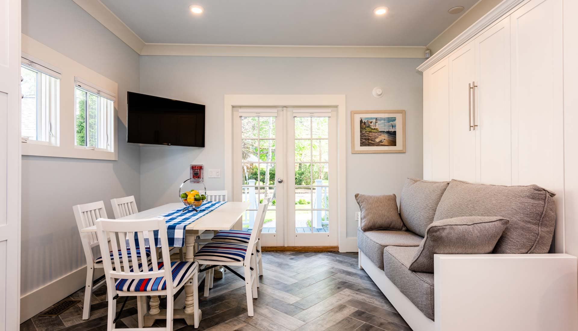 Bright, modern dining area featuring a table, white chairs, a cozy sofa, and access to a garden through double doors.